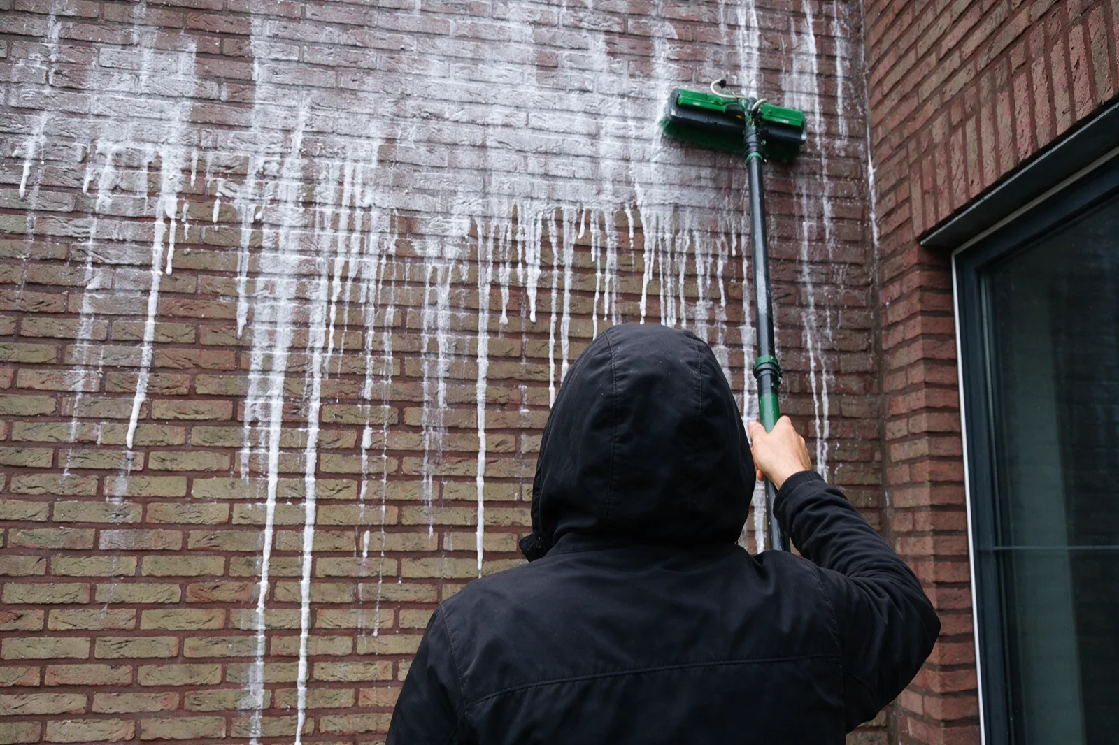 Gevelreiniging van een bakstenen rijwoning met borstel op lage druk